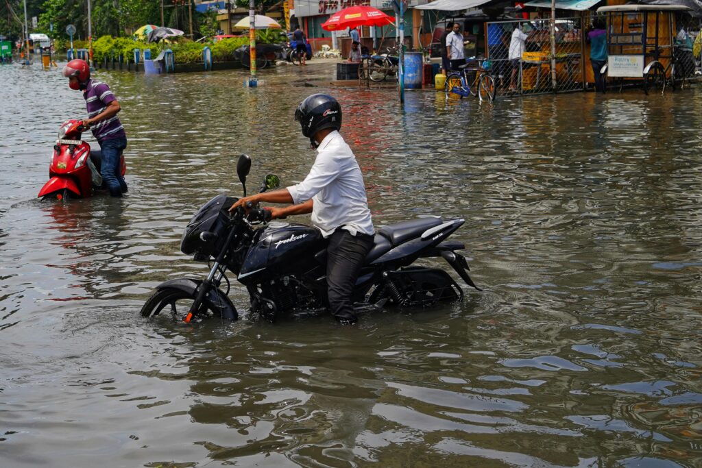 Motorcyclists navigate through a flooded street in Kolkata, India.