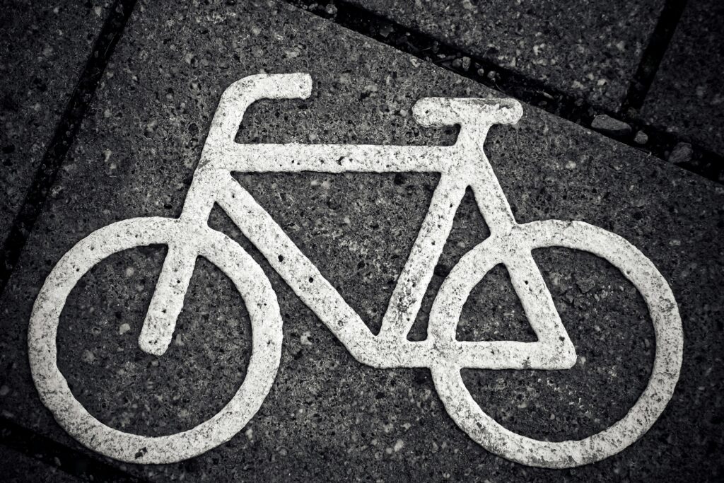 Black and white image of a bicycle symbol on city pavement, emphasizing urban cycling.