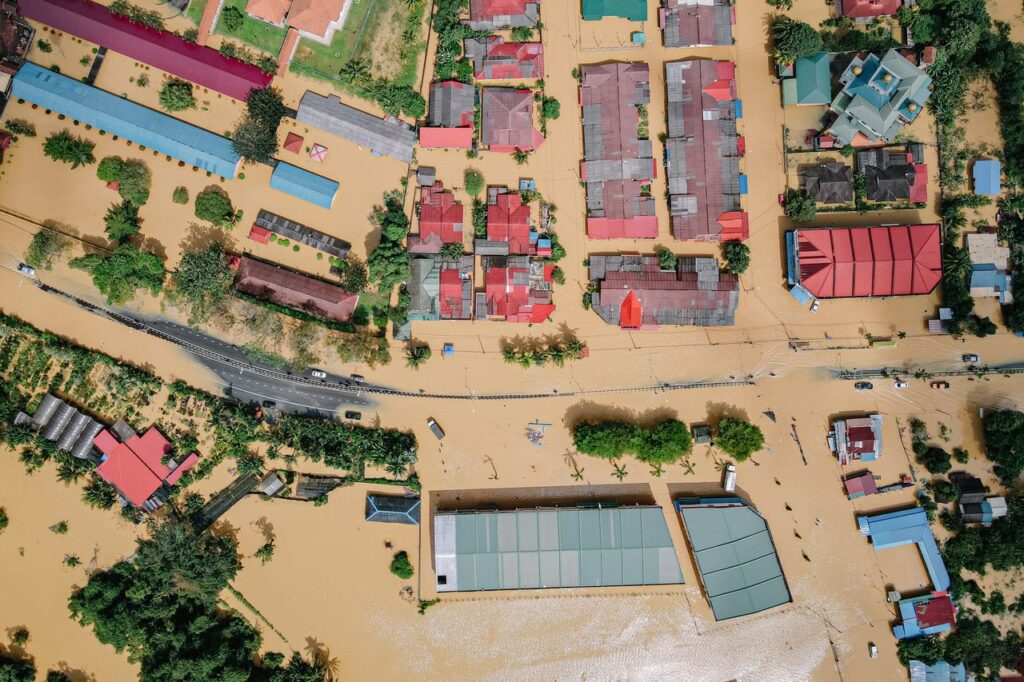 From above of residential buildings and lush green trees in flooded small town